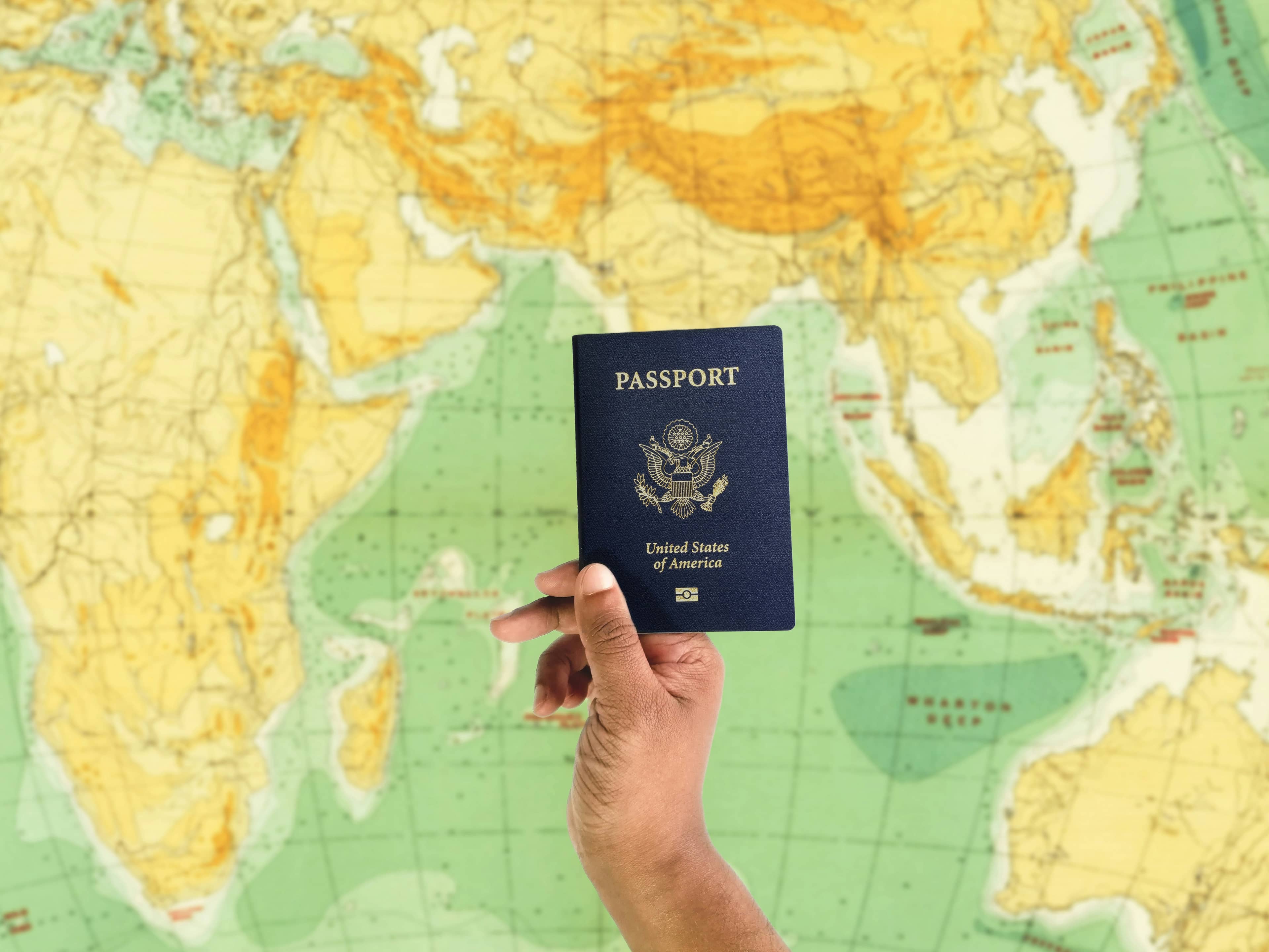A United States passport held above a world map